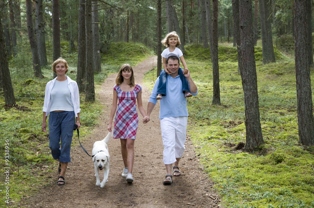 Fototapeta premium Happy family with dog walking in the forest