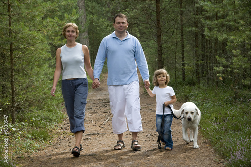 Happy family with dog walking in the forest
