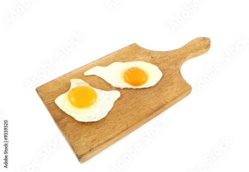two fried eggs on wooden board
