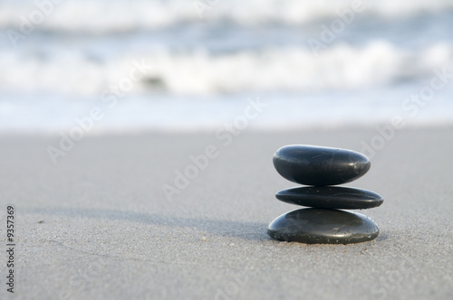 Black smooth pebbles  on a sandy beach.