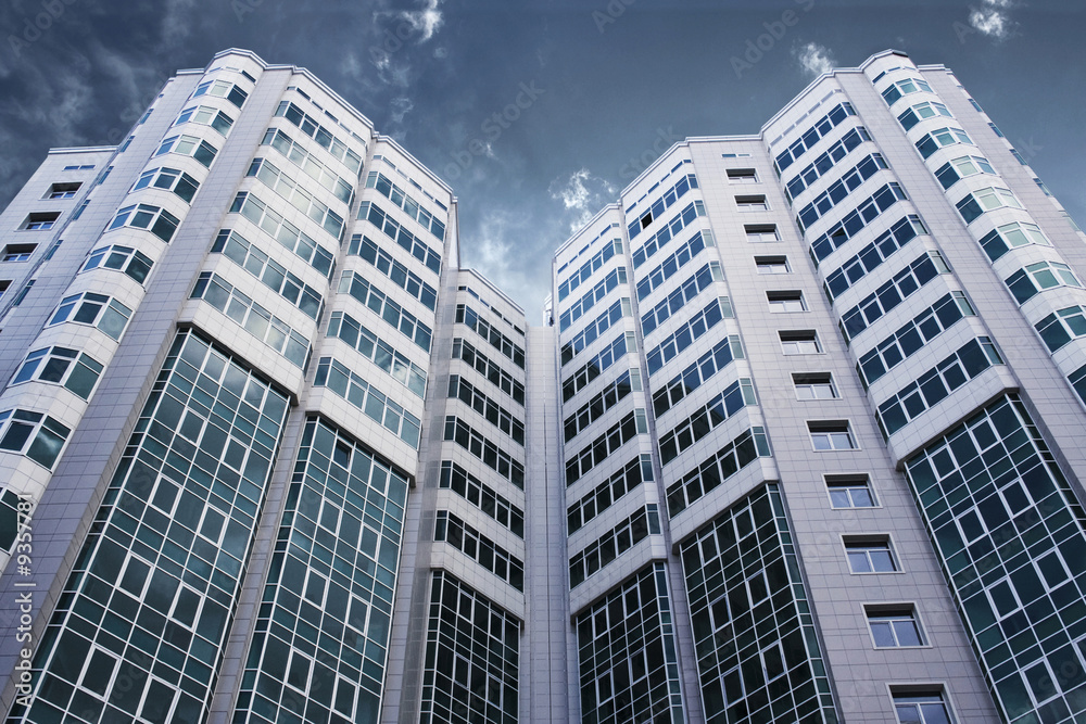 Fototapeta premium Modern glass business center with dramatic sky