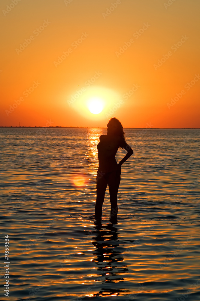 Silhouette of the young woman on a gulf on a sunset