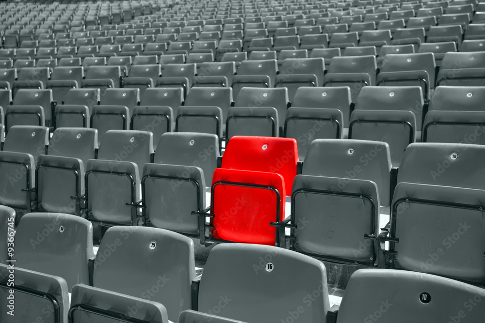black and white picture of stadium seat with only one red Stock
