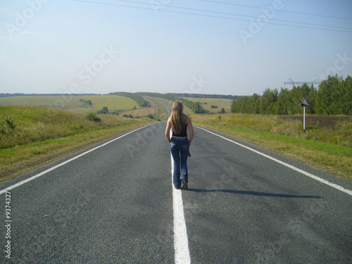 girl going  far on  road on background  blue sky....