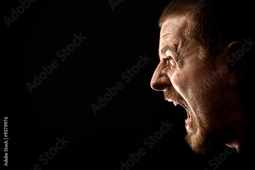 Fotografia Twarz gniewny mężczyzna krzyczeć odizolowywam na czerni