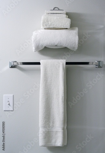 Three white terry cloth towels on towel rack and towel holder