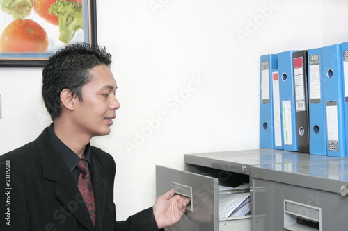 business man in office opening file cabinet