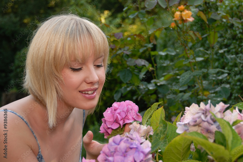 young blond girl in garden smelling flower young blond girl in garden smelling flower