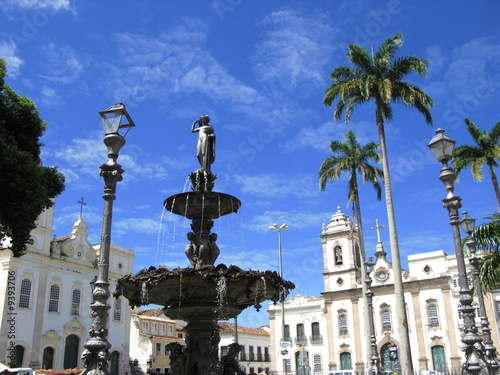 Fontaine, cocotiers et église sur une place de Bahia, Brésil