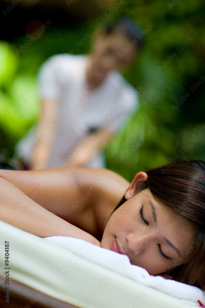 Obraz premium A young woman having massage outside in tropical garden