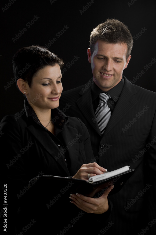Satisfied business executives looking at notebook Satisfied business executives looking at notebook