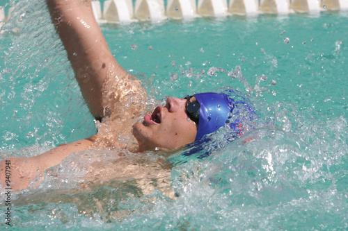 Swimmers swimming backstroke event in blue water