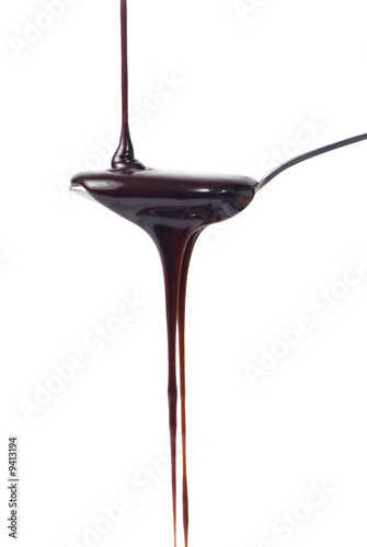 An inviting spoonful of chocolate syrup being poured out.