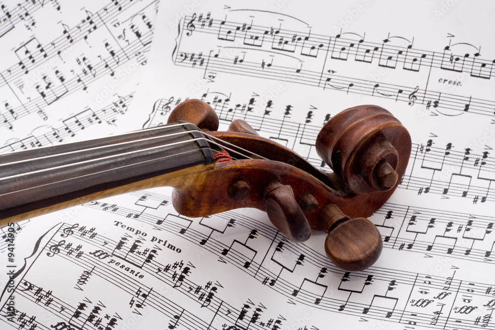 Naklejka premium Old violin scroll on a sheet music