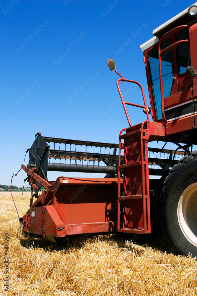 Fototapeta premium combine harvester closeup on field under blue sky
