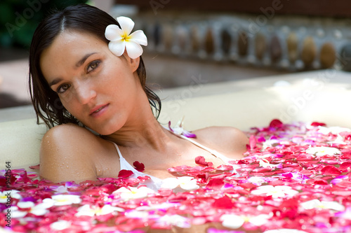 A young woman in a bath full of flowers