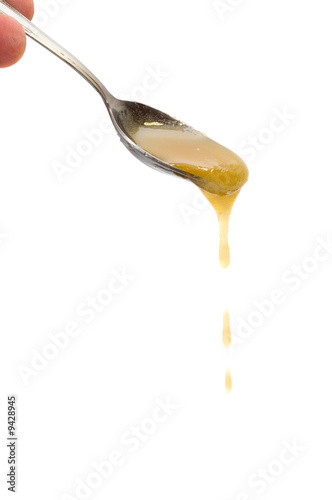 Honey drip from spoon on white background
