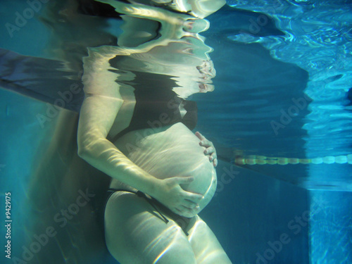 Babybauch einer schwangeren Frau unter Wasser im Pool photo