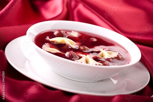 Cherry soup with pasta on the red satin