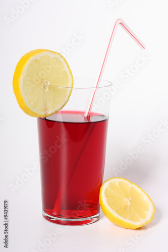 Glass of hibiscus tea with straw and two lemon slices