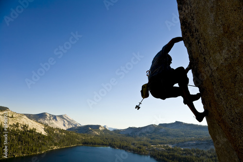 A rock climber desperately clinging to a rock face.