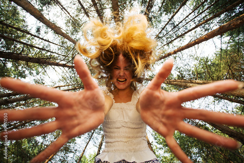 Agressive woman stretch her hands to camera at piny forest