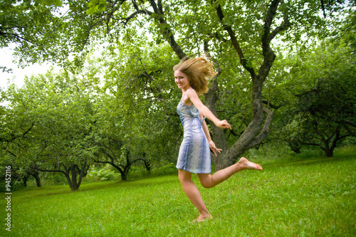 Young happy beautiful woman runing at park with apple trees