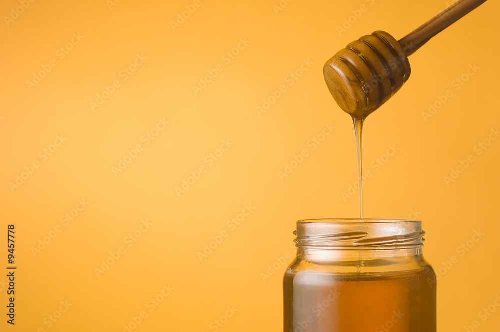 Honey falling from a dipper into a jar Honey falling from a dipper into a jar