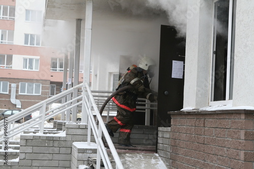 Firefighter pulling hose into blazing building