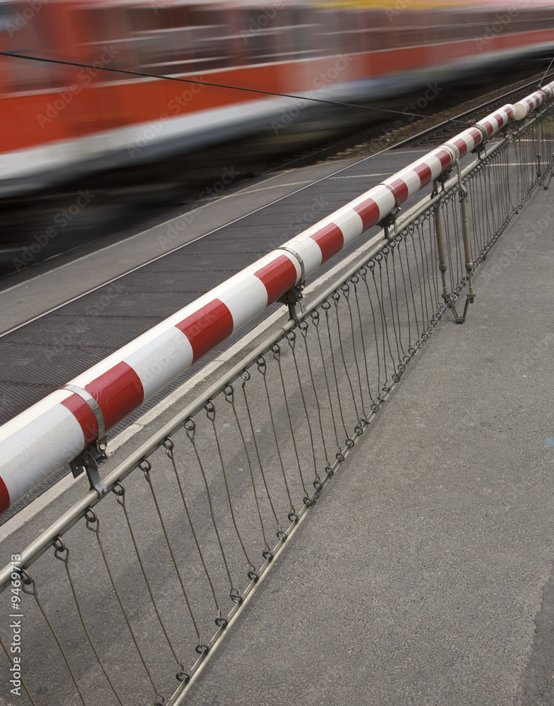 Obraz premium geschlossene Bahnschranke mit vorbeifahrendem Zug