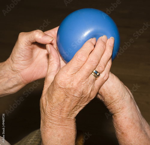 hands of seniors do gymnastics with a blue ball photo