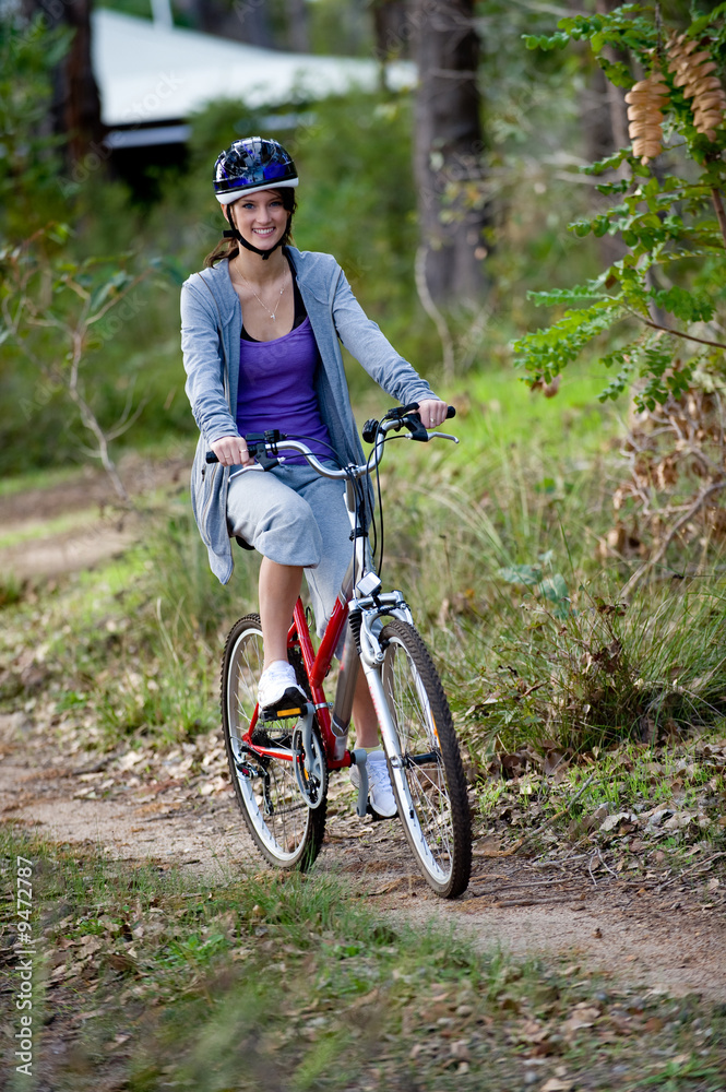 Obraz premium A young woman riding a bicycle in the woods