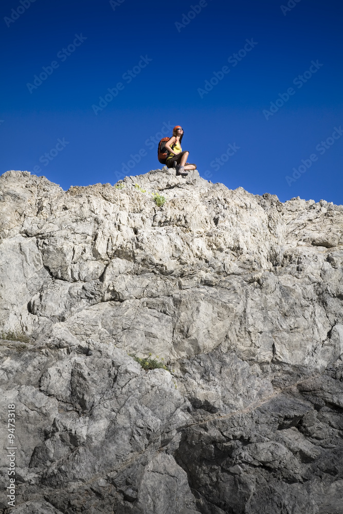 young woman resting on top of the mountain after hiking
