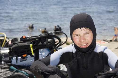 Photography young diver on the sea beach, near scuba gear