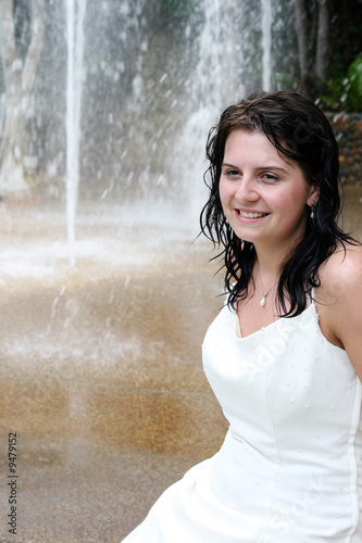 Beautiful young bride next to a waterfall on her wedding day.