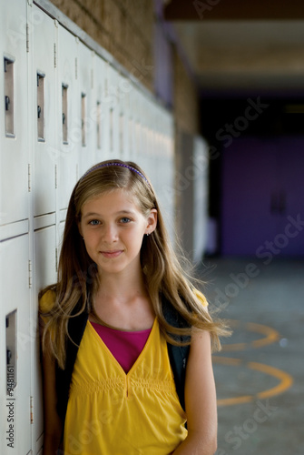Obraz na plátně Cute preteen, teen or tween blonde standing against her locker.