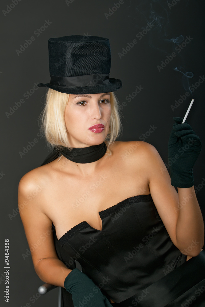 Young blonde woman in black hat keeps a cigarette thoughtfully. Young blonde woman in black hat keeps a cigarette thoughtfully.