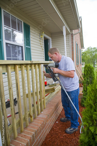 Carpenter is adding rails to porch on front of house