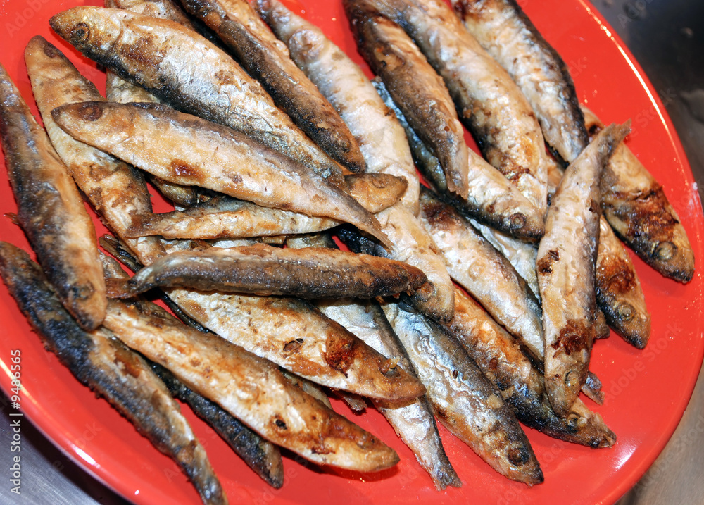 heap of small fried fish on red plate heap of small fried fish on red plate