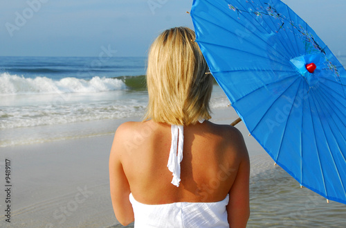 Woman holding umbrella looking at ocean photo