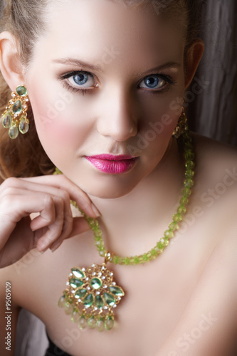 Beautiful blond woman with green necklace and earring