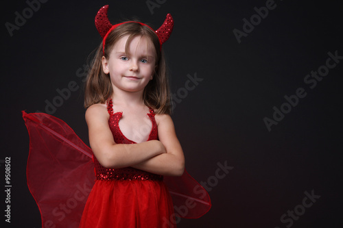 Happy little girl in devil Halloween costume.