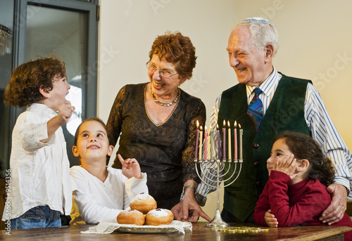grandperents and grandchildren lightening Hanukkiyah together
