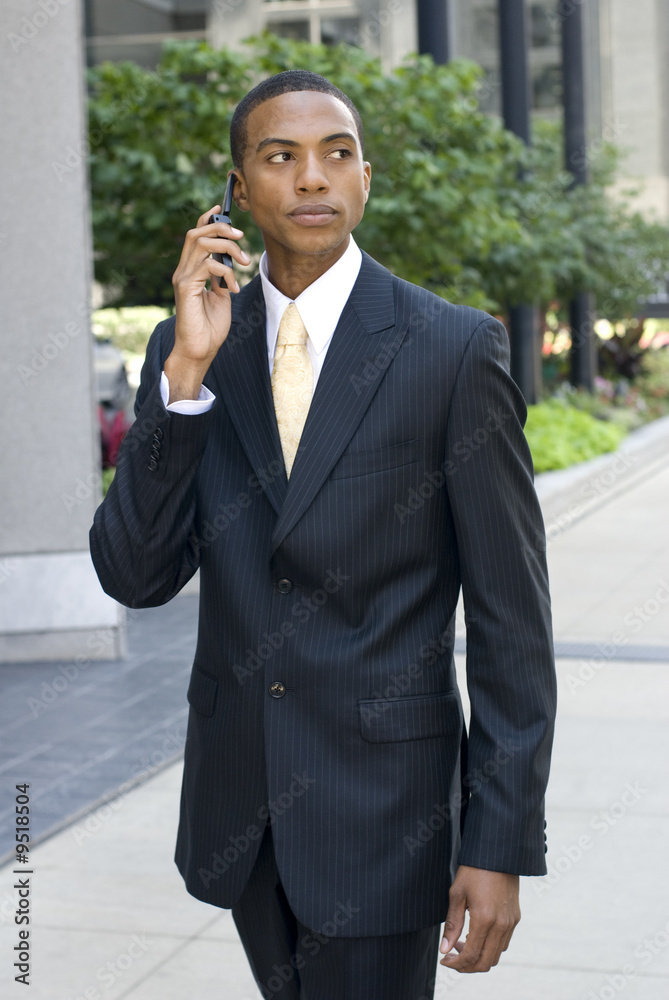 Model in business suit walking while talking on a cell phone Model in business suit walking while talking on a cell phone