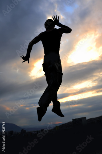 young man dancing and jumping on top of the building