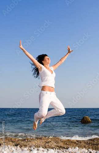 happy young woman is jumping in the beach