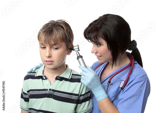A female  doctor or nurse,  looks inside the ears of a boy.