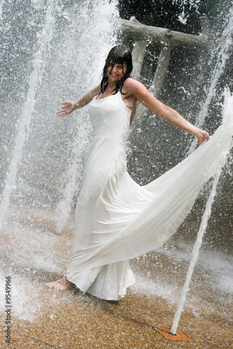 Fototapeta Naklejka Na Ścianę i Meble -  Beautiful young bride playing in a waterfall on her wedding day.