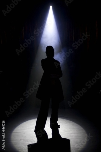 A silhouette of a person under an entertainment light.