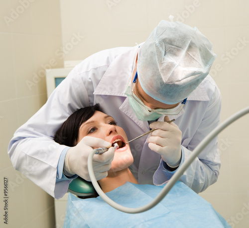 Photo of dentist examining oral cavity of young female